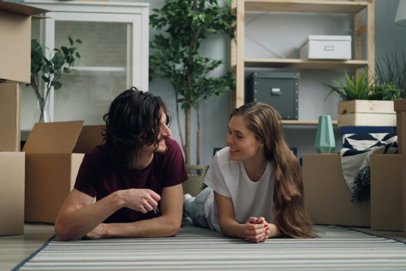 Young couple relaxing on the floor surrounded by moving boxes in their new home.