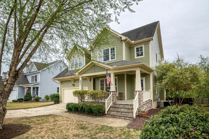 Spacious suburban house with a porch, garden, and an American flag prominently displayed.