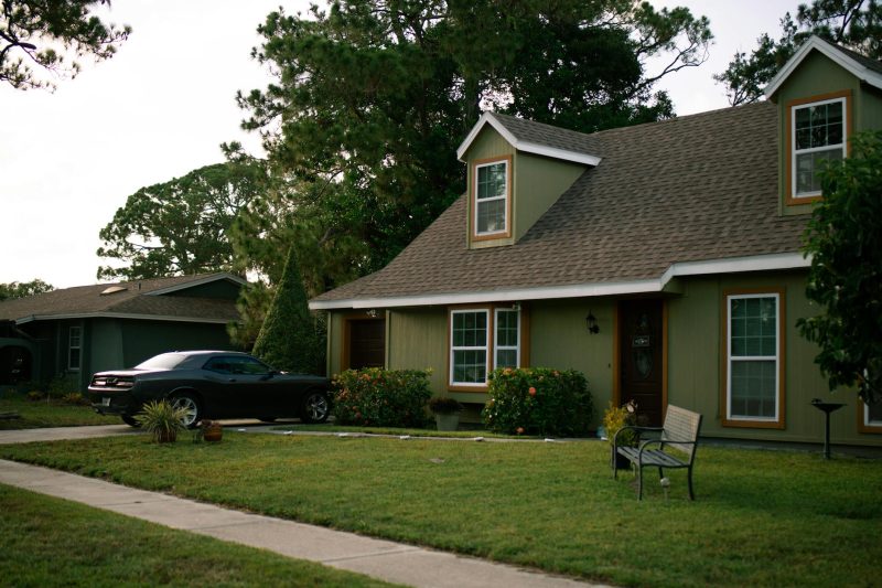 Suburban home with a manicured lawn and parked car, showcasing residential comfort and tranquility.