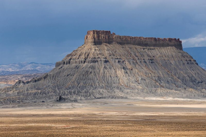 Stunning Factory Butte in the Utah desert beneath a dramatic, cloud-filled sky.