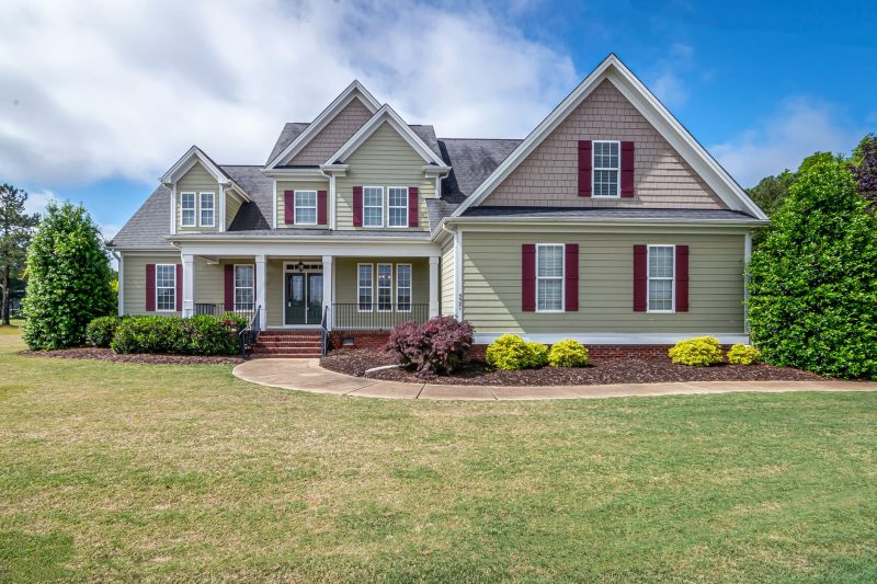 Two-story suburban house with a manicured lawn and welcoming front porch.