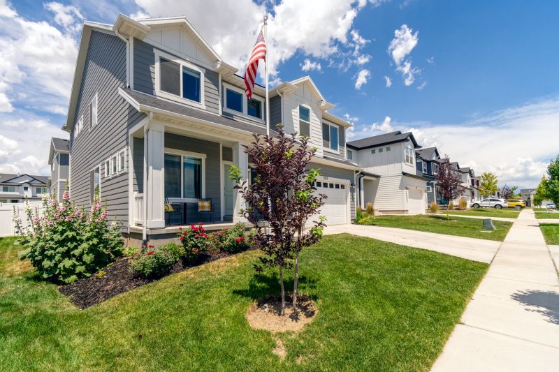 Modern suburban house with a landscaped garden and an American flag, featuring stylish architecture.