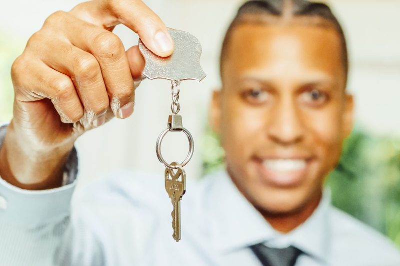 Blog 1 A cheerful real estate agent holds up a house key, smiling and indicating a sense of excitement.