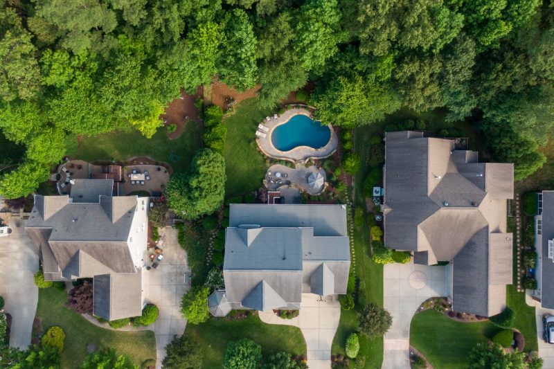 Aerial view of a suburban neighborhood with green backyards and a swimming pool in Wake Forest, NC.