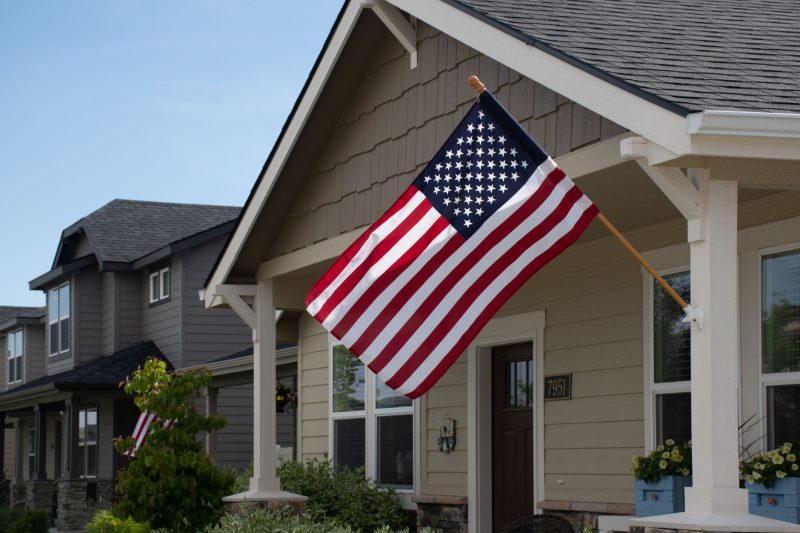 Vibrant American flag hanging outside a stylish suburban house during daylight.